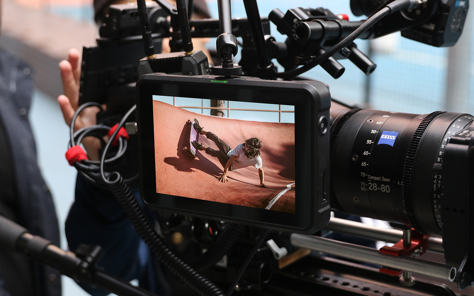 Atomos Shinobi 7 promotional image showing the monitor setup for a camera assistant on the side of the camera with a cine arm mount.