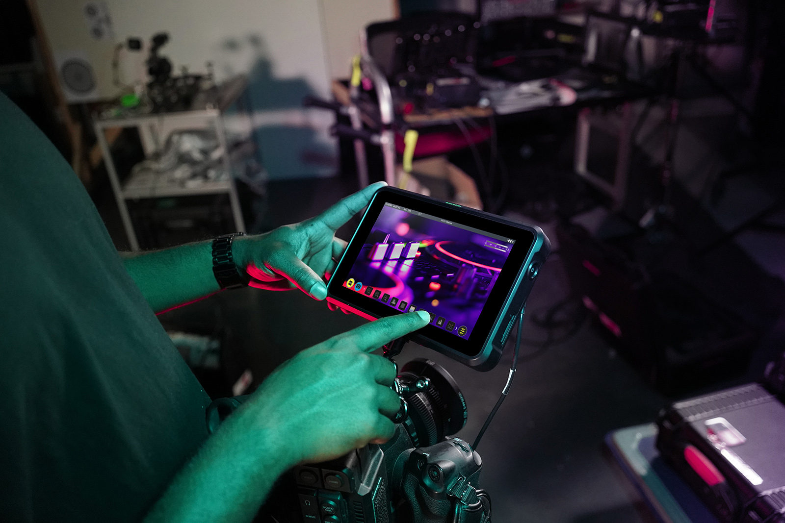 Atomos Shinobi 7 promotional image showing man utilizing the touch function on an on-camera monitor setup with equipment in the background.