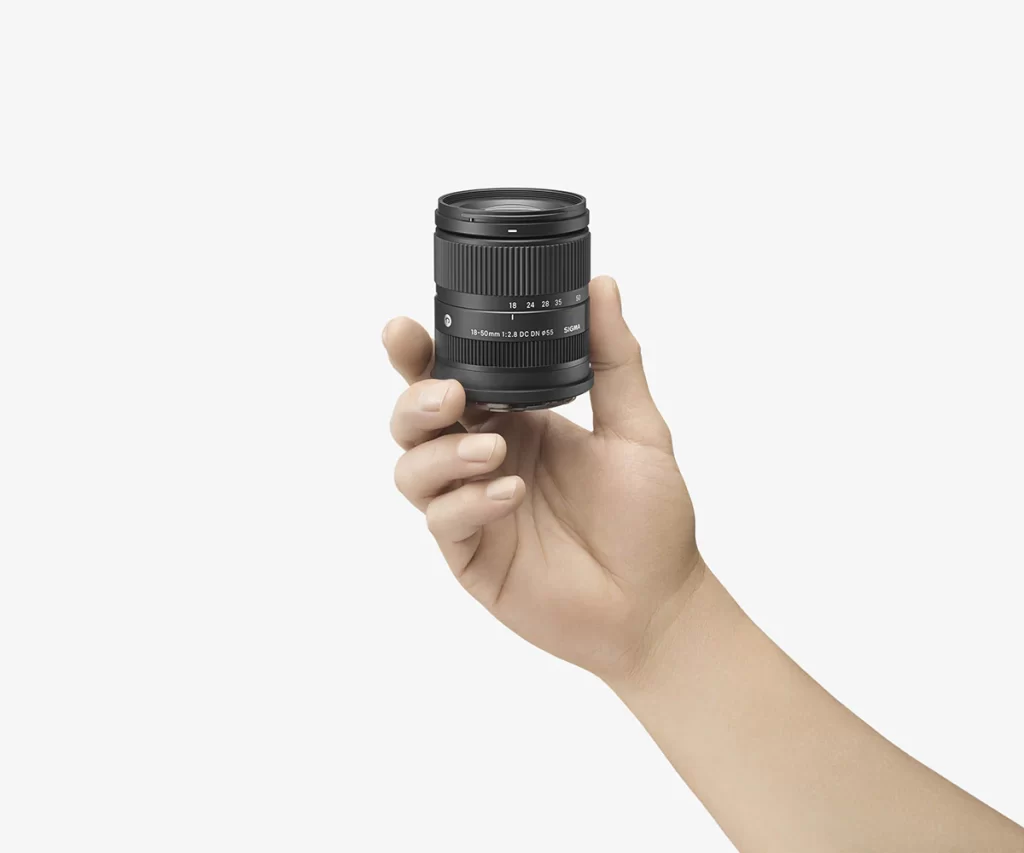An image showing a man holding the very small Sigma 18-50mm F2.8 DC DN Contemporary Lens in his hand to demonstrate its small size.